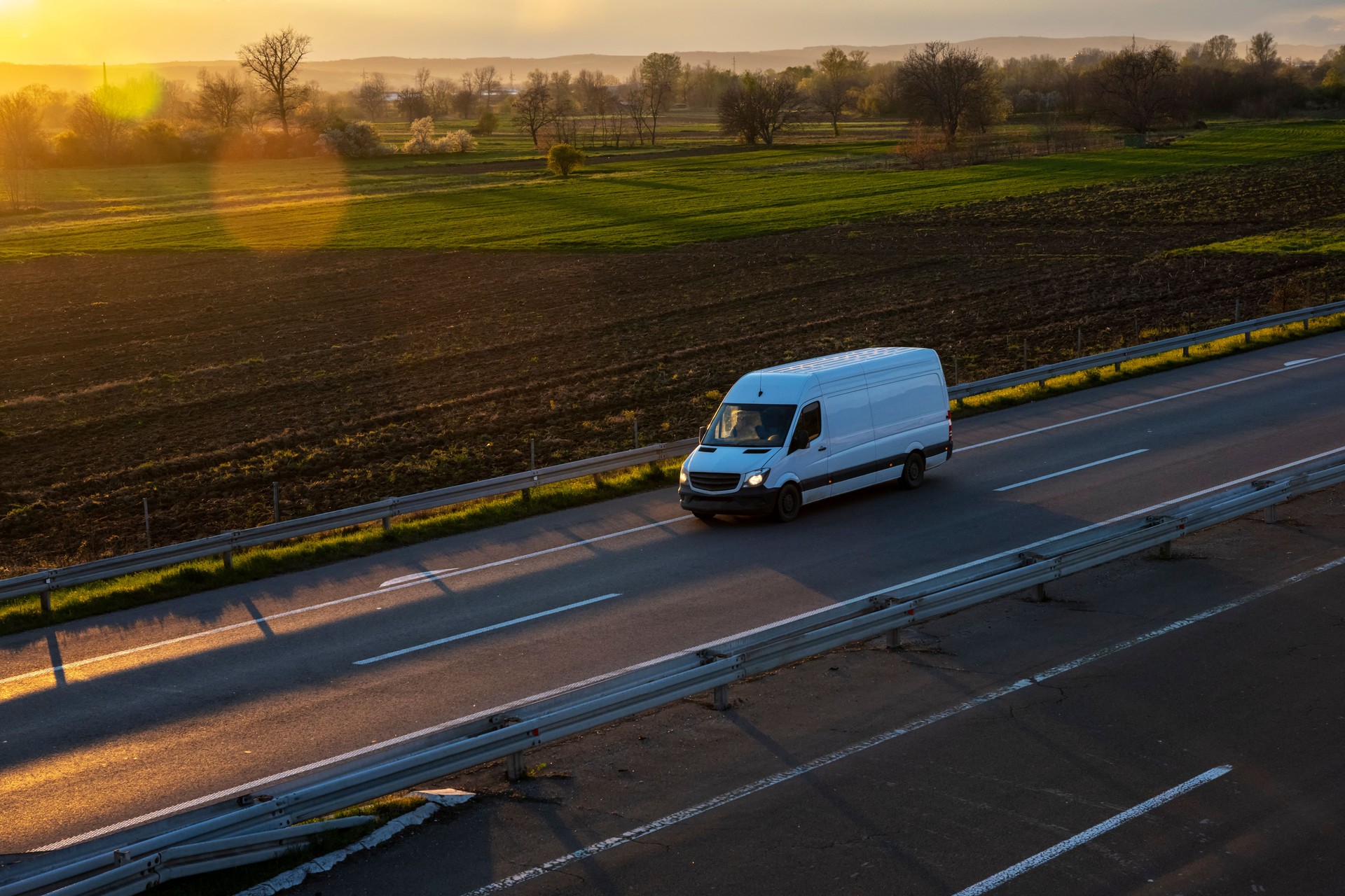 White delivery van on the highway. White modern delivery small shipment cargo courier van moving fast on motorway road to city urban suburb. The world's best transport of goods.